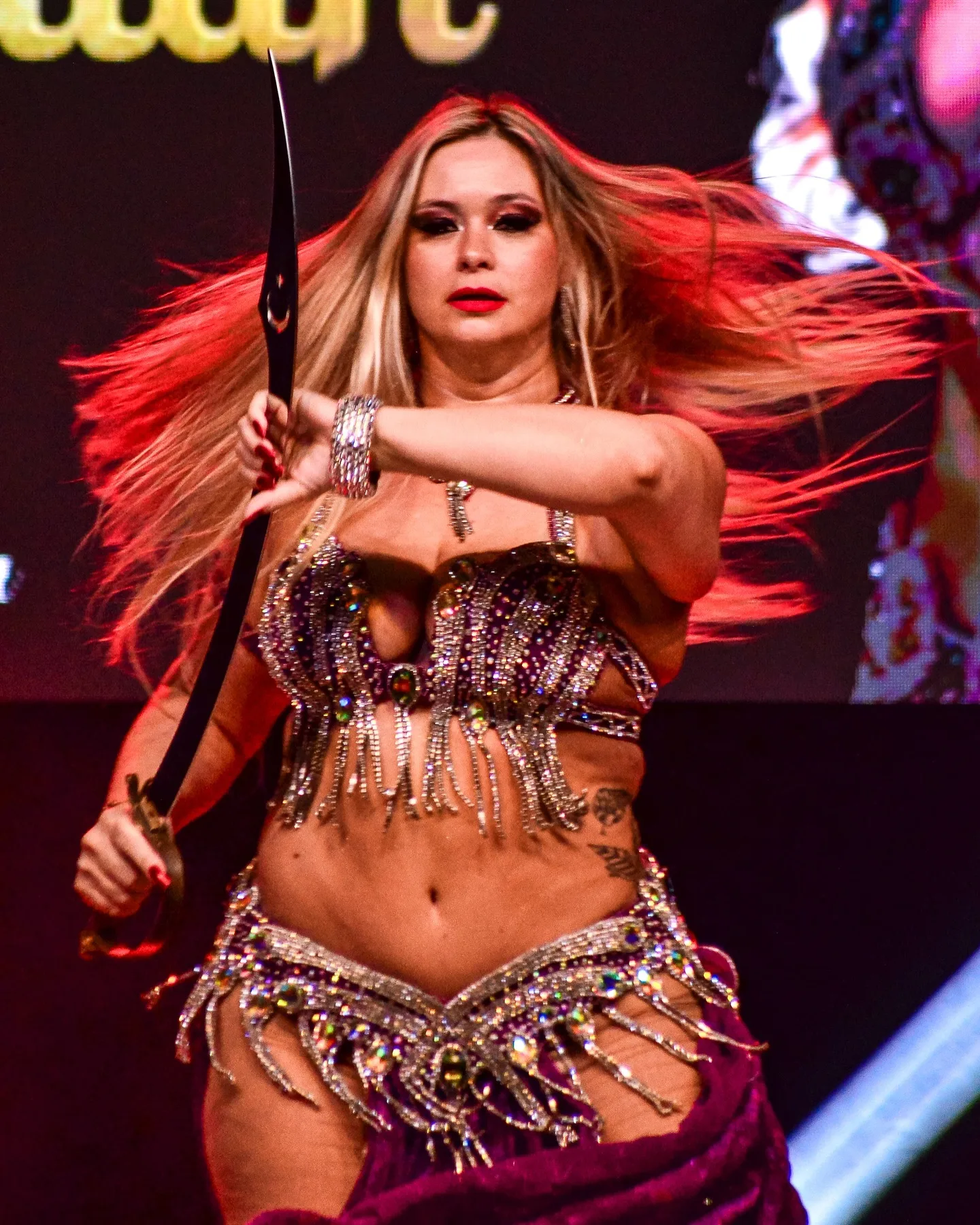 Dançarina com saia vermelha e os braços à frente durante apresentação.