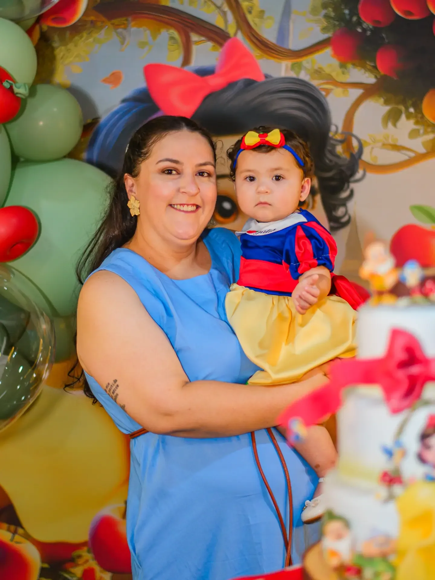 Criança no colo de uma mulher durante festa de aniversário.