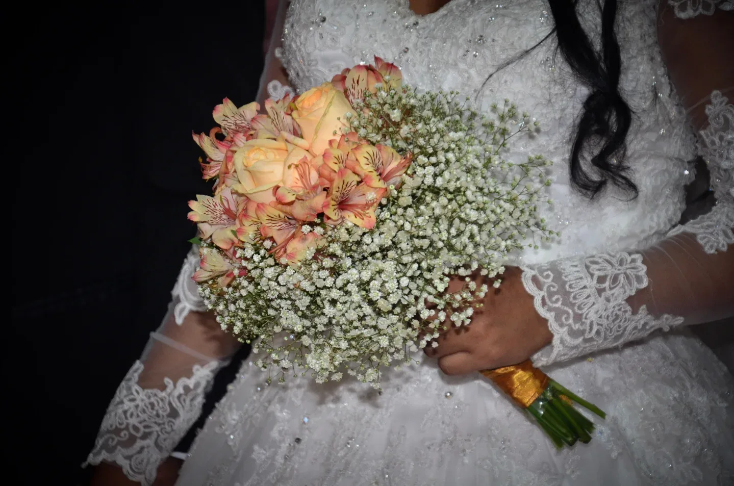 Detalhe de buquê sobre vestido de noiva.
