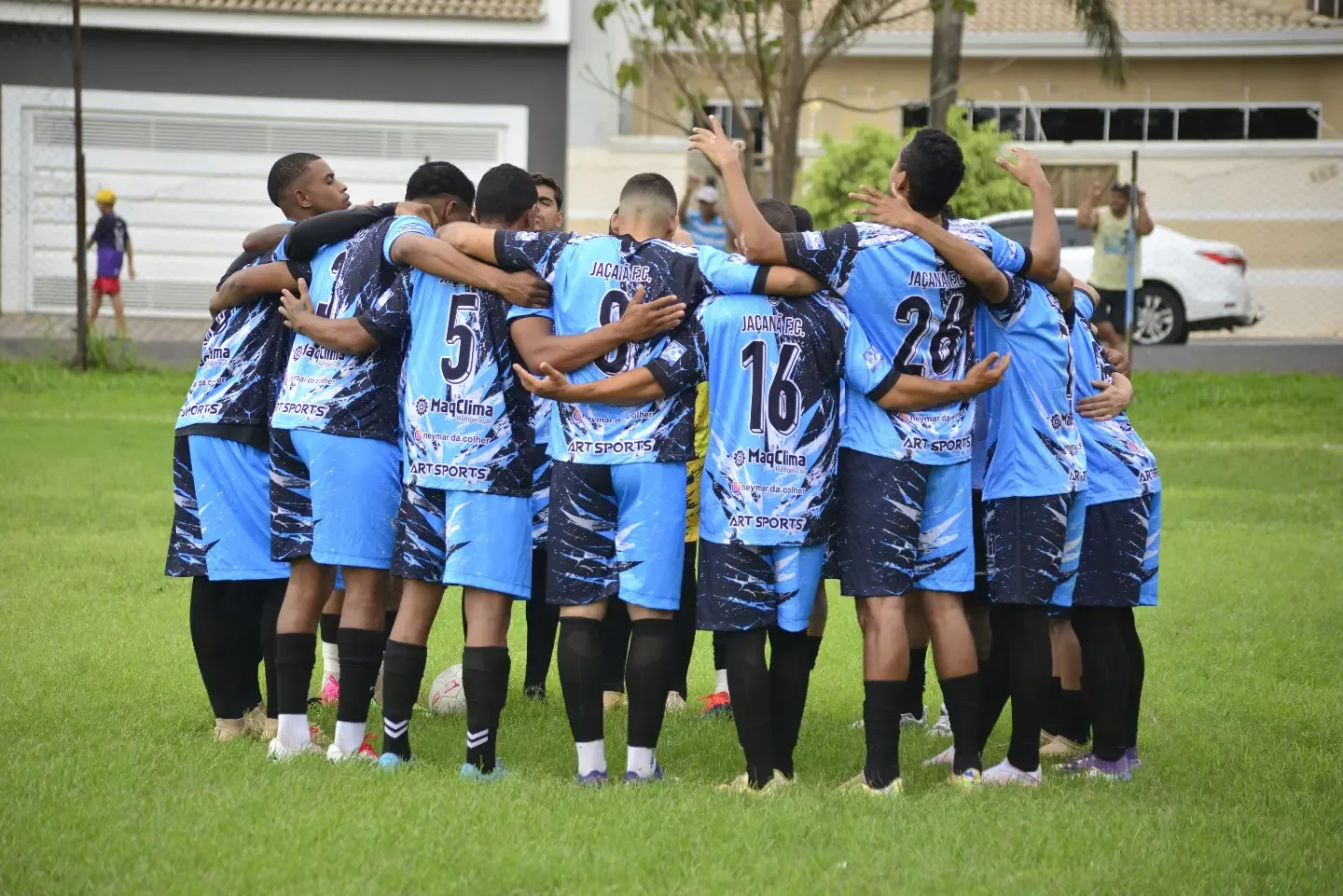 Jogadores de futebol reunidos em círculo no gramado.