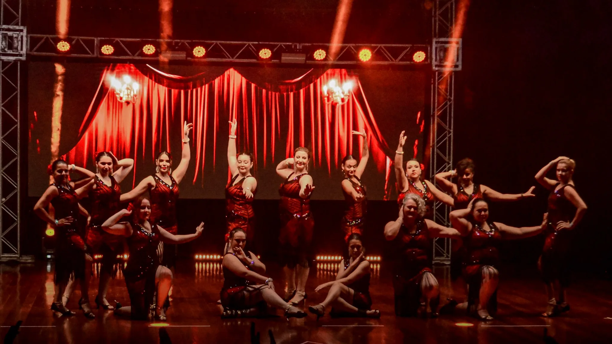 Apresentação de dança com figurinos e iluminação vermelhos.