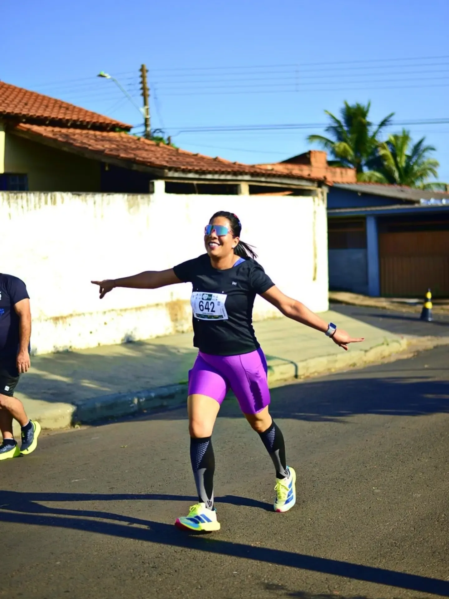 Participante de corrida com os braços abertos em uma rua.