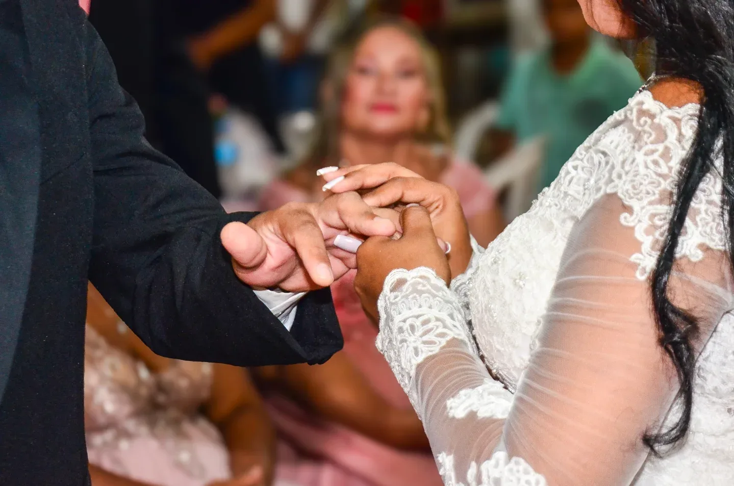 Detalhe das mãos do casal durante a troca de alianças.