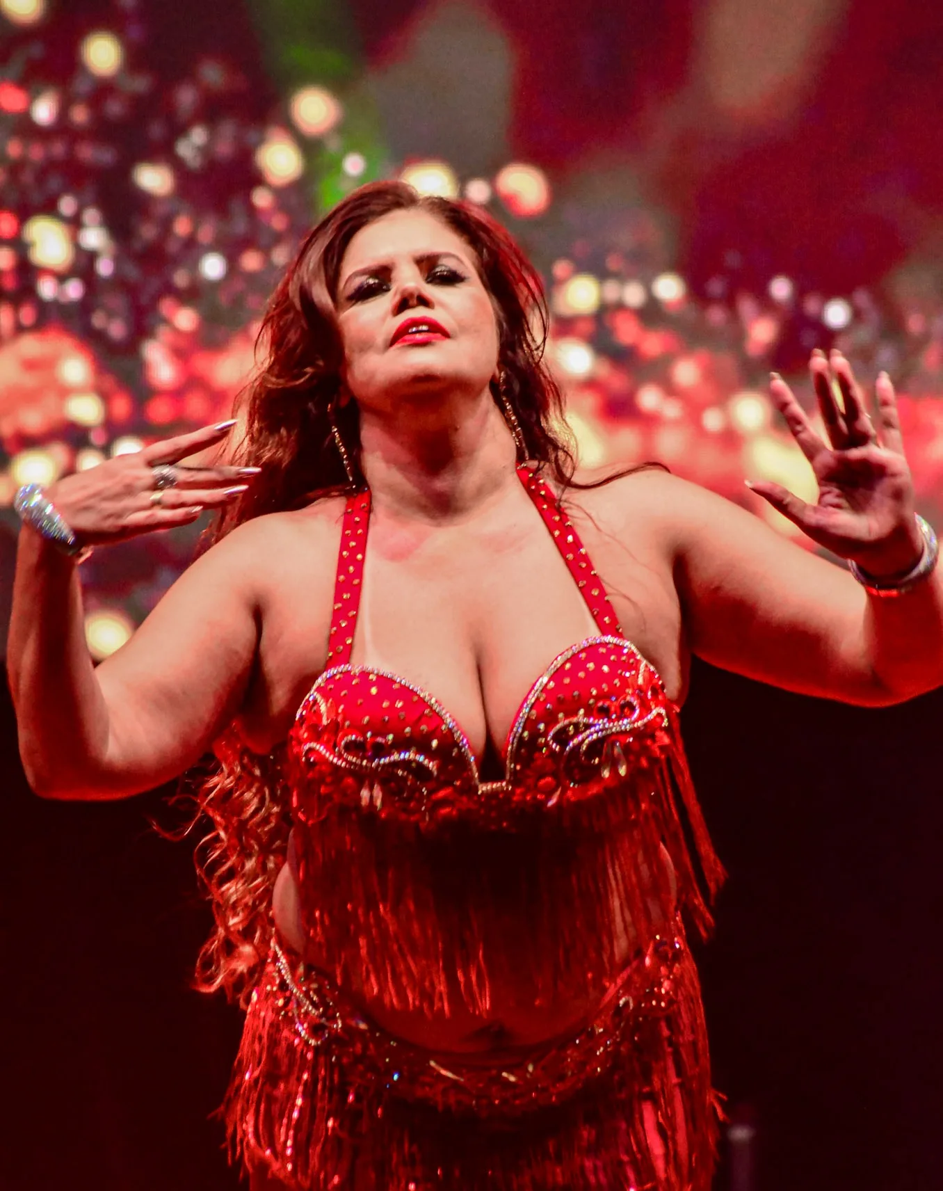 Dançarina com figurino vermelho sob a iluminação do palco.