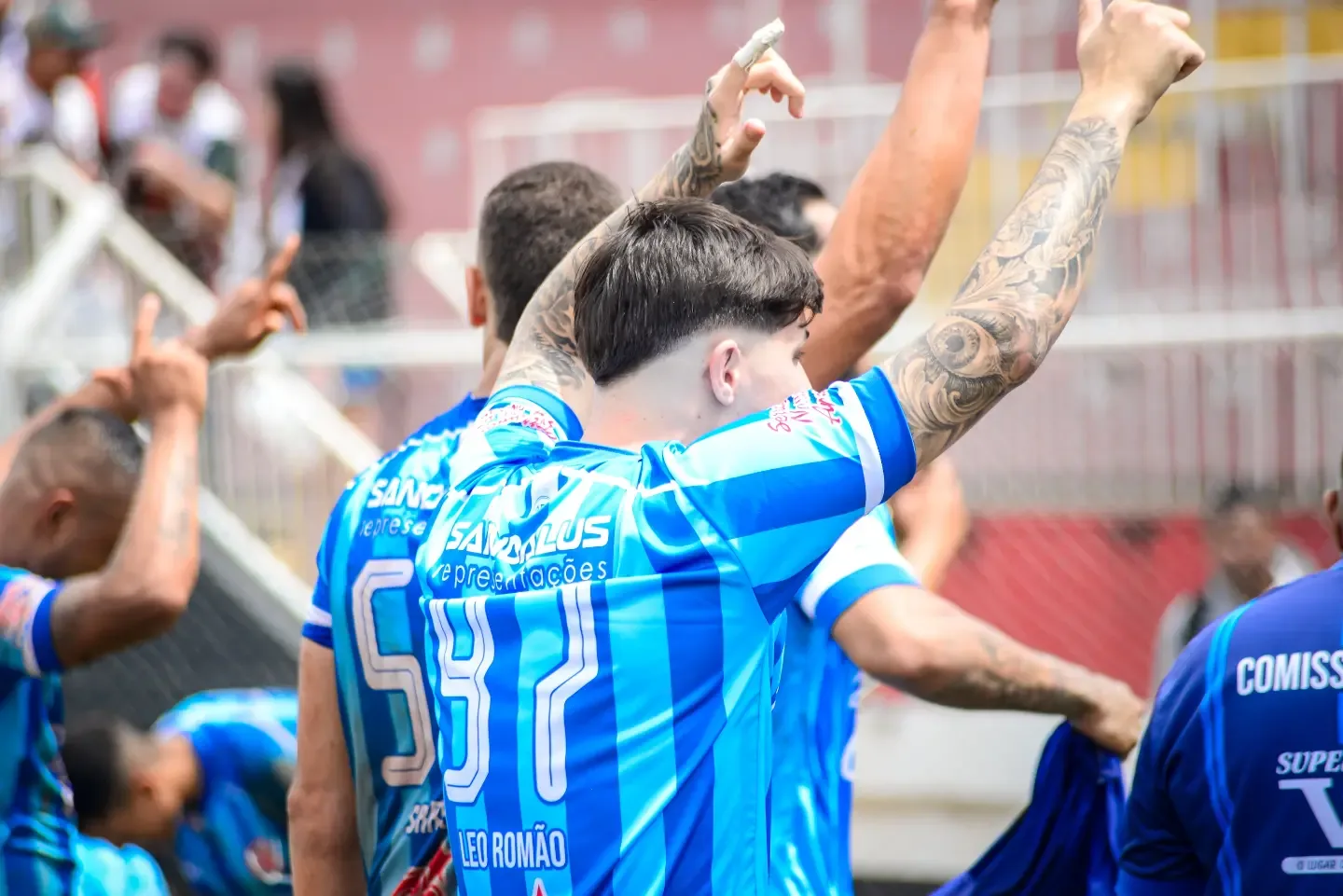 Jogador de uniforme azul de costas, com os braços erguidos.