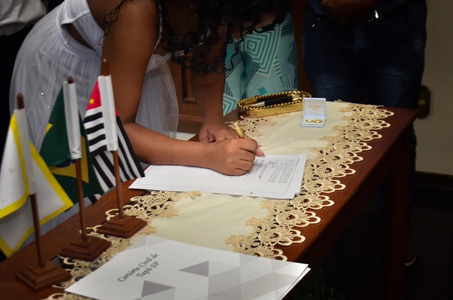 Noiva assinando um documento sobre uma mesa.
