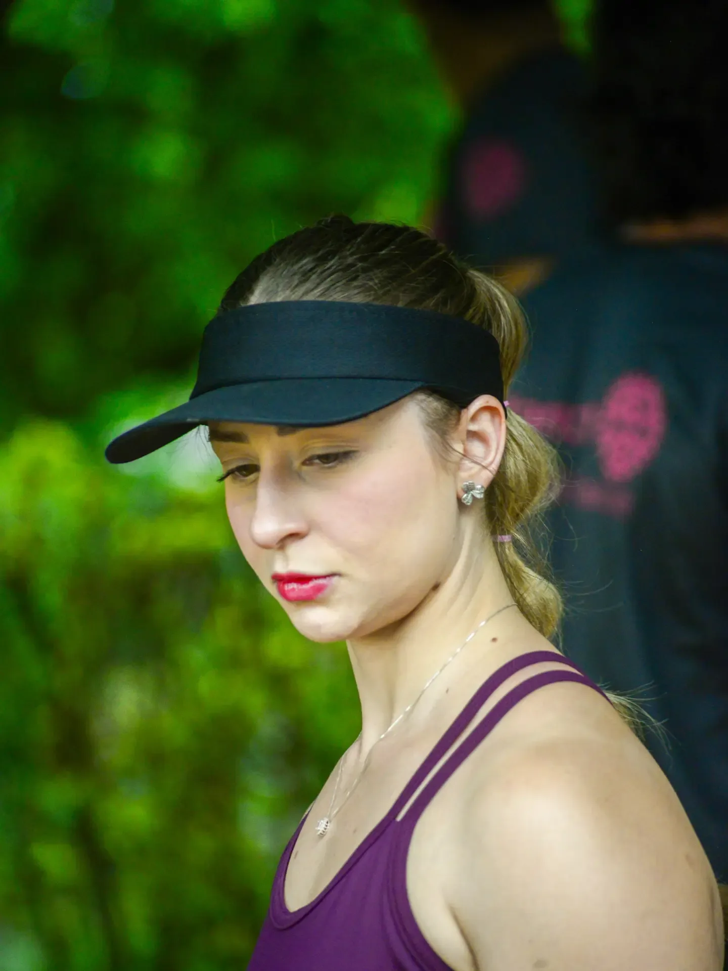 Participante de evento esportivo com boné preto diante de vegetação.