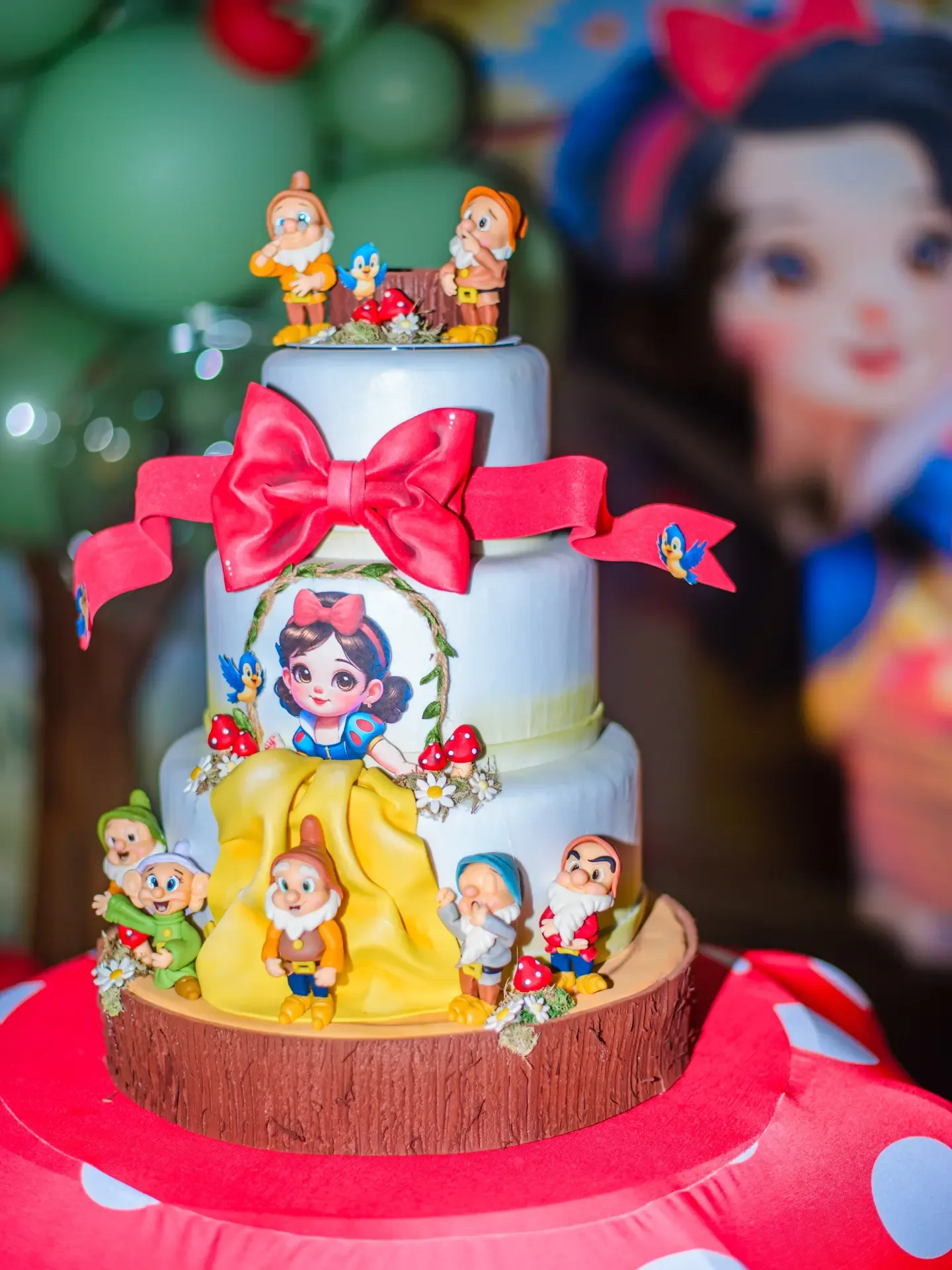 Detalhe de bolo de aniversário com laço vermelho.