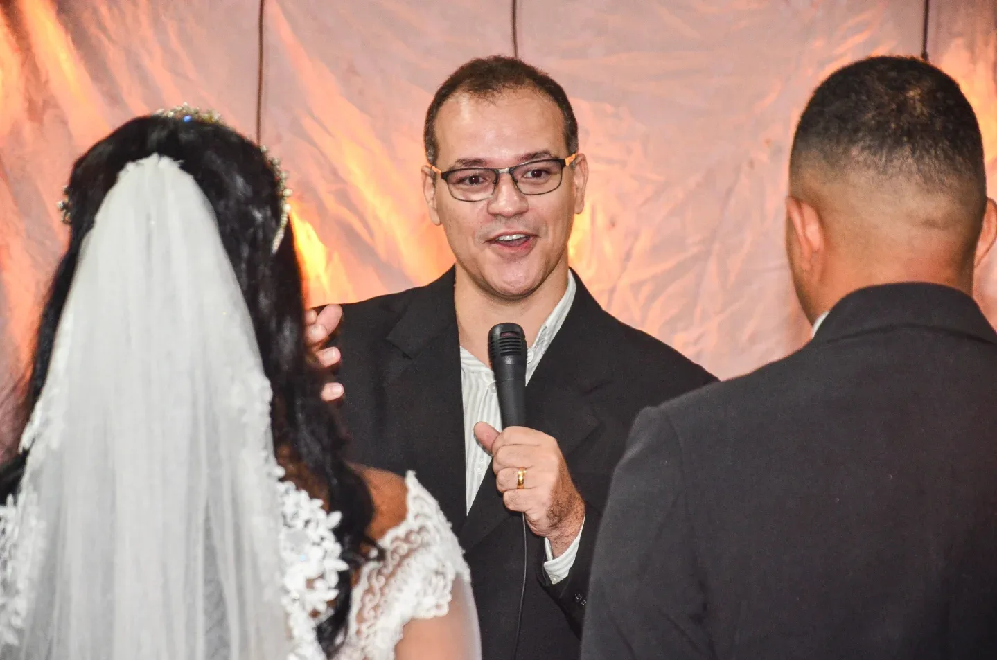 Casal diante do celebrante durante cerimônia de casamento.