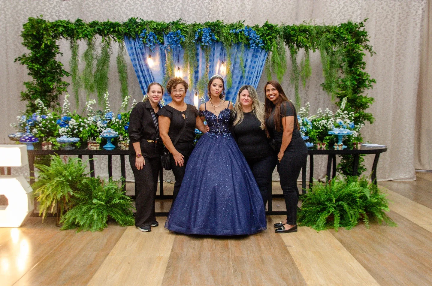 Grupo de pessoas diante de painel de plantas em uma festa.