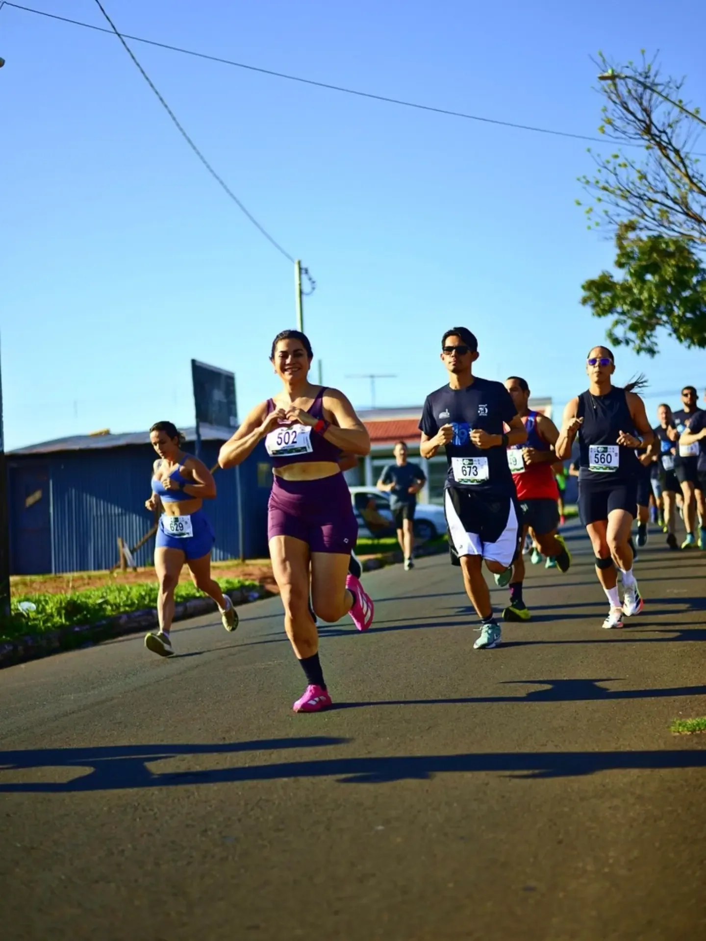 Participantes de corrida em uma rua sob céu azul.