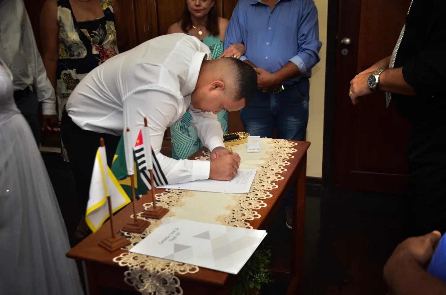 Noivo assinando um documento durante cerimônia de casamento.