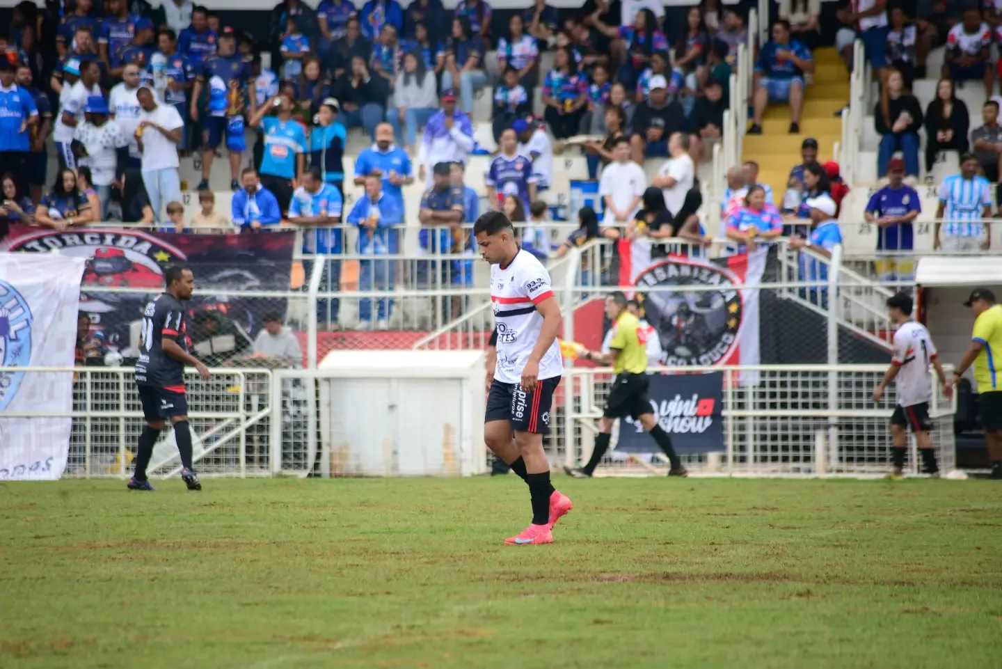 Jogador de futebol em campo diante da arquibancada.