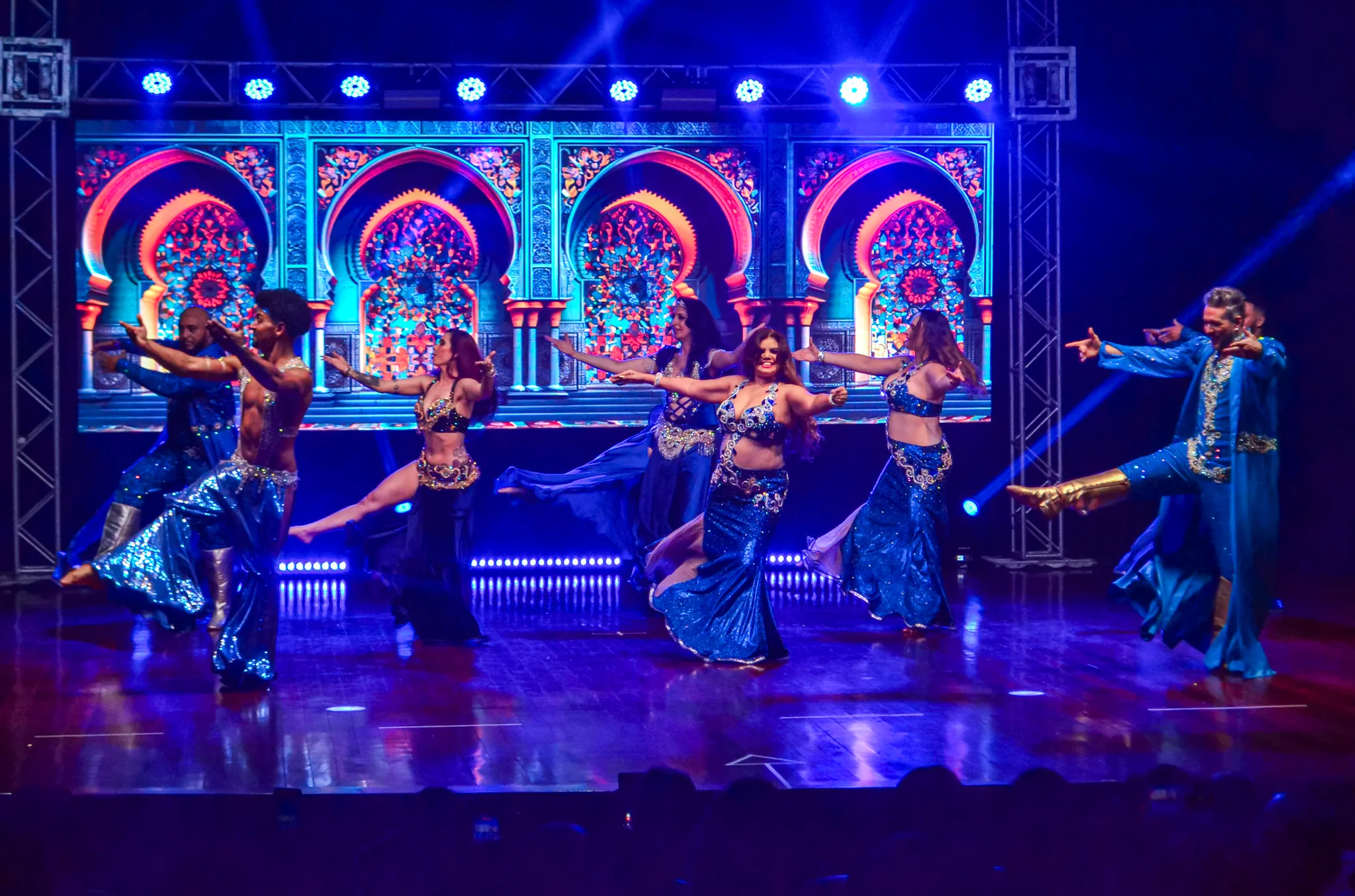 Apresentação coletiva de dança sob refletores azuis.