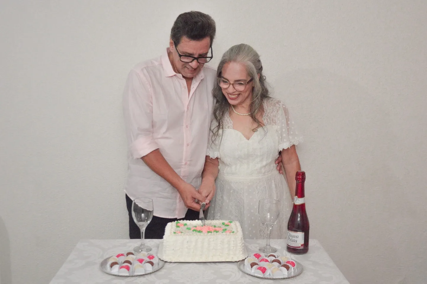 Casal cortando um bolo durante celebração de casamento.