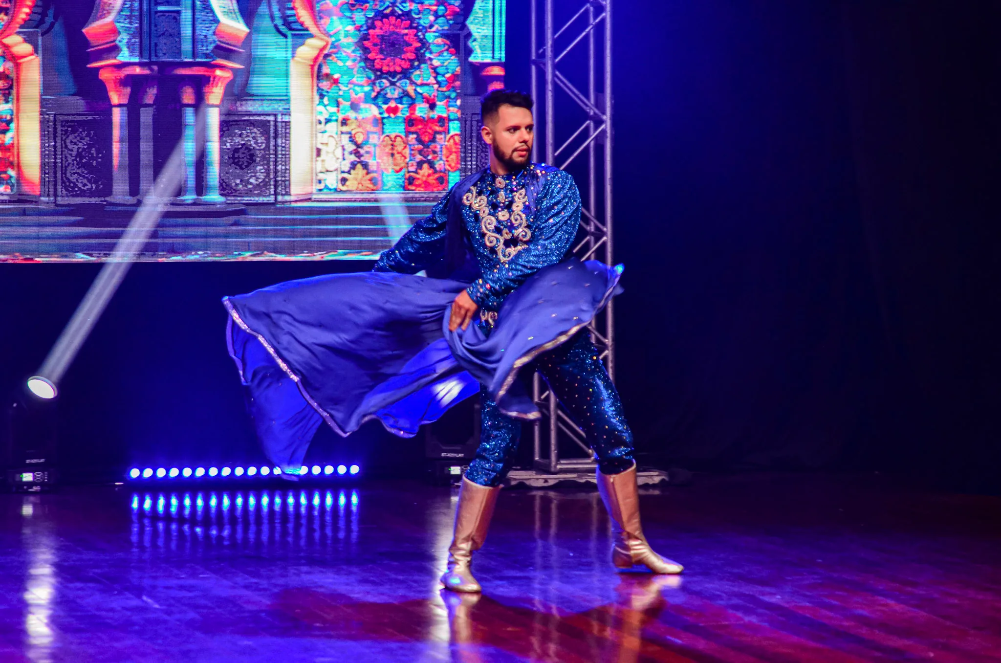 Artista movimentando tecido azul durante apresentação no palco.