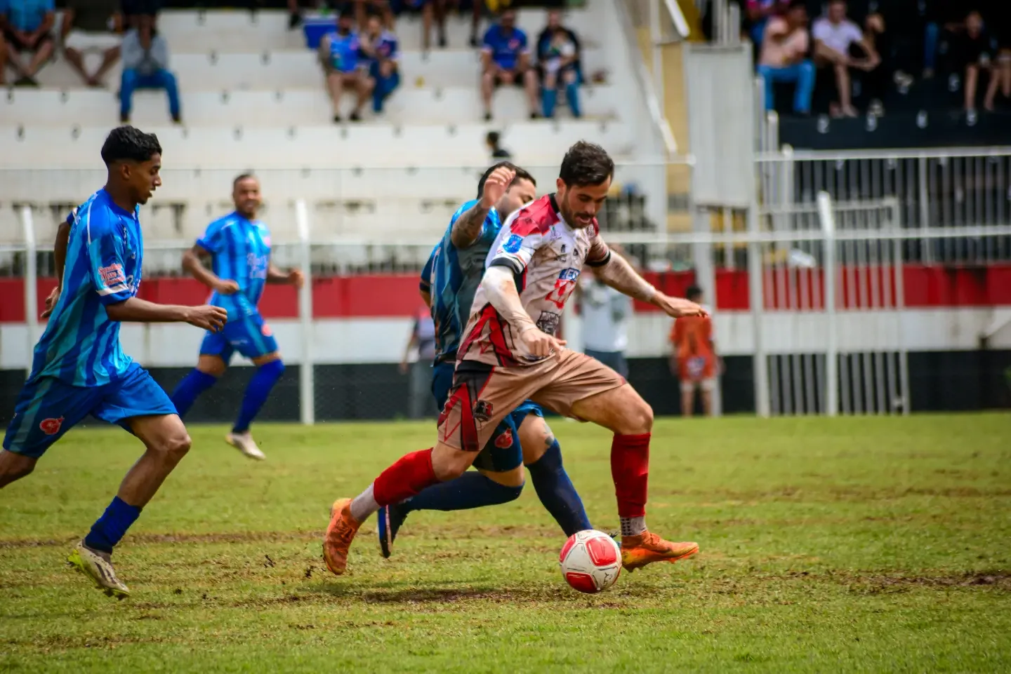 Jogadores de futebol disputando a bola no gramado.