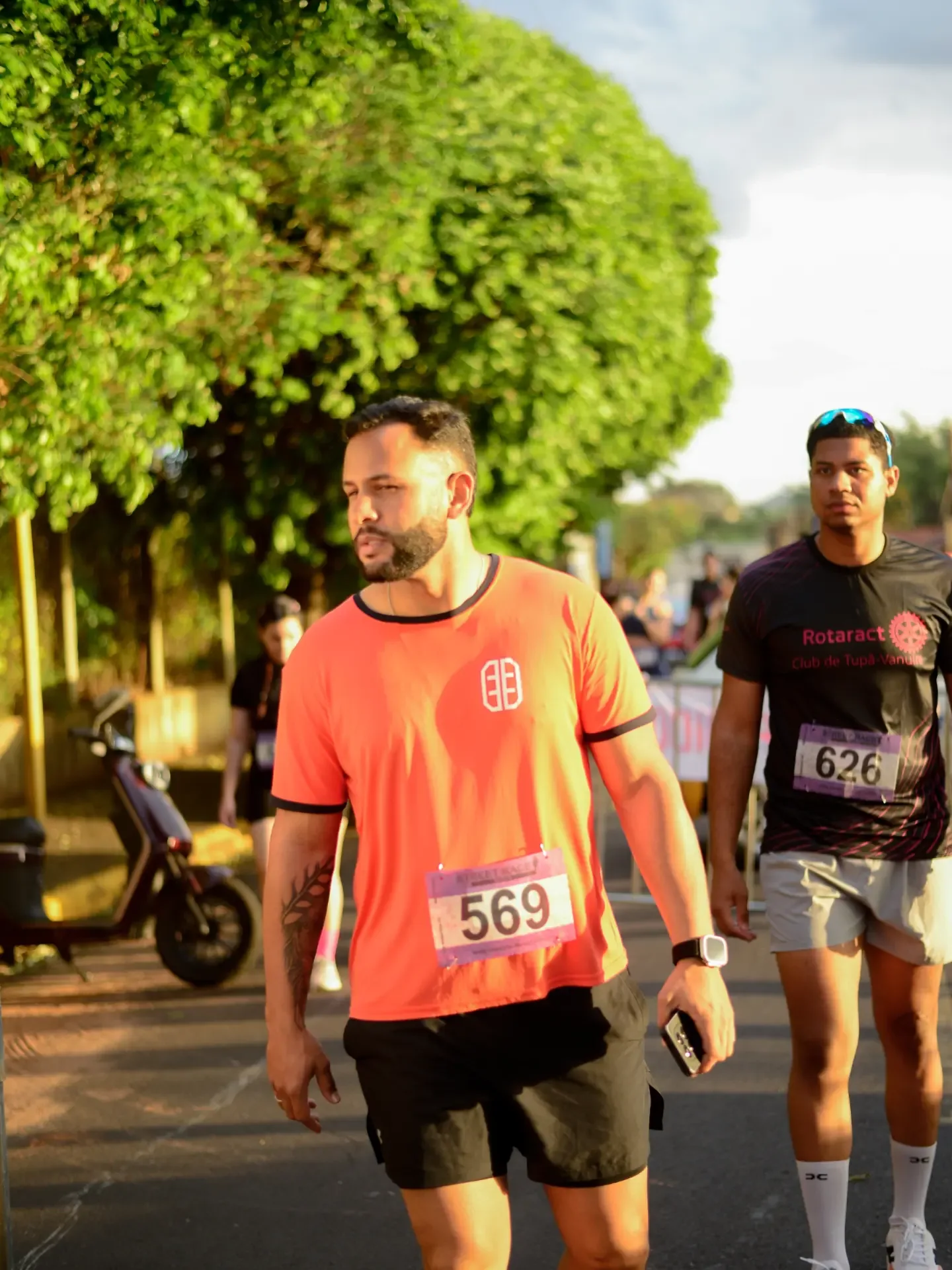 Corredor com camiseta laranja durante uma prova na rua.