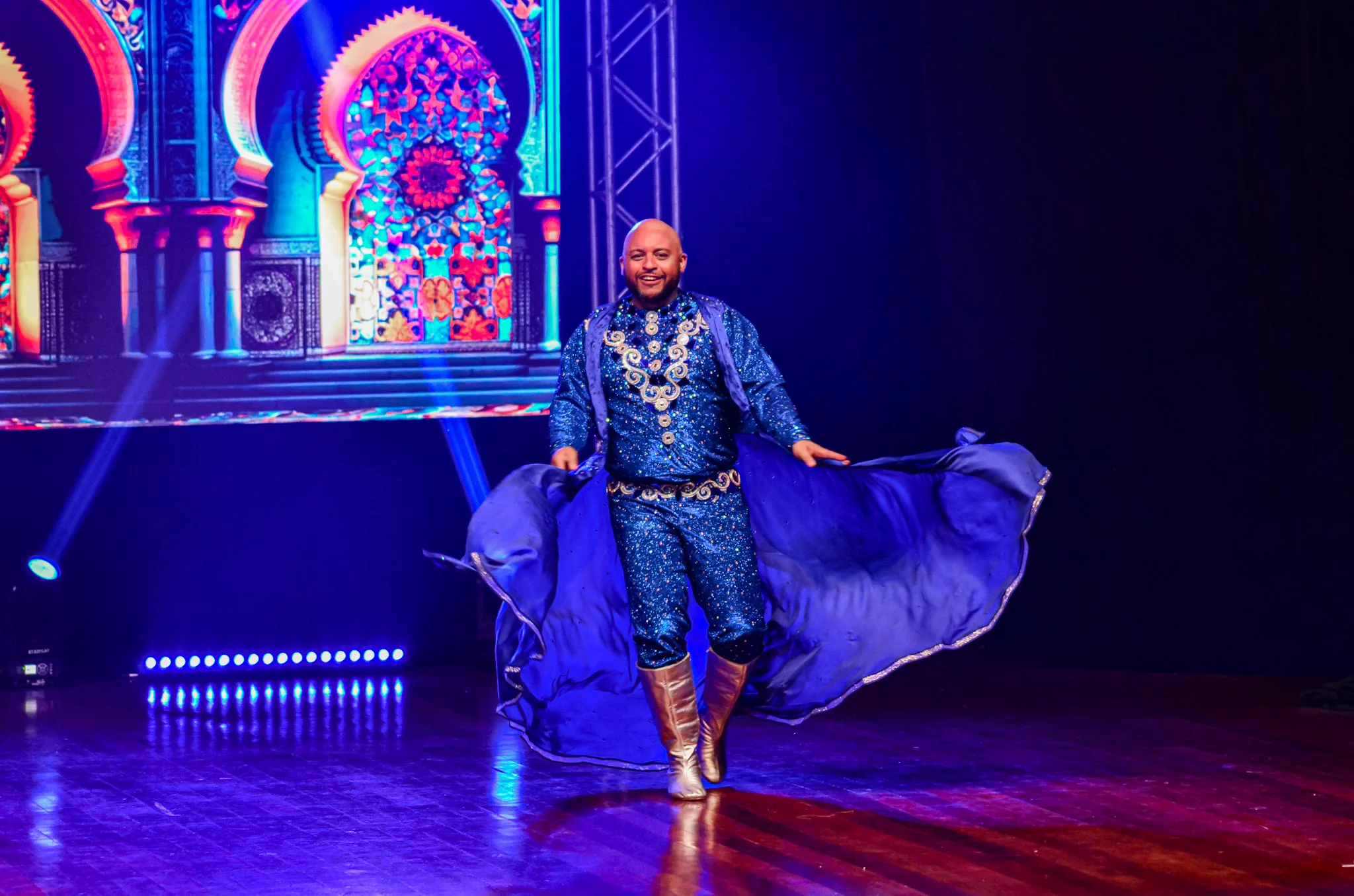 Artista com figurino azul durante giro no palco.
