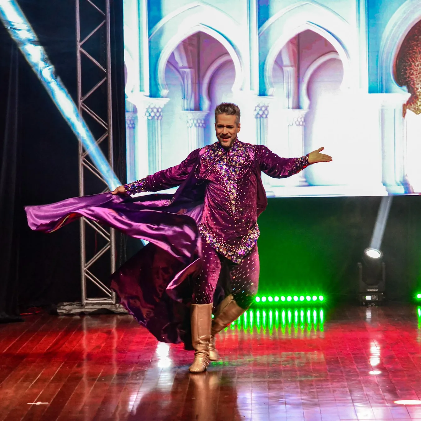 Artista movimentando tecido roxo durante apresentação no palco.